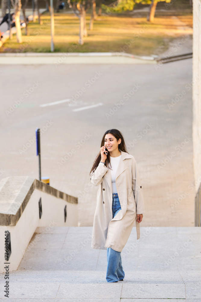 female arab student climbs stairs while talking on phone on university campus