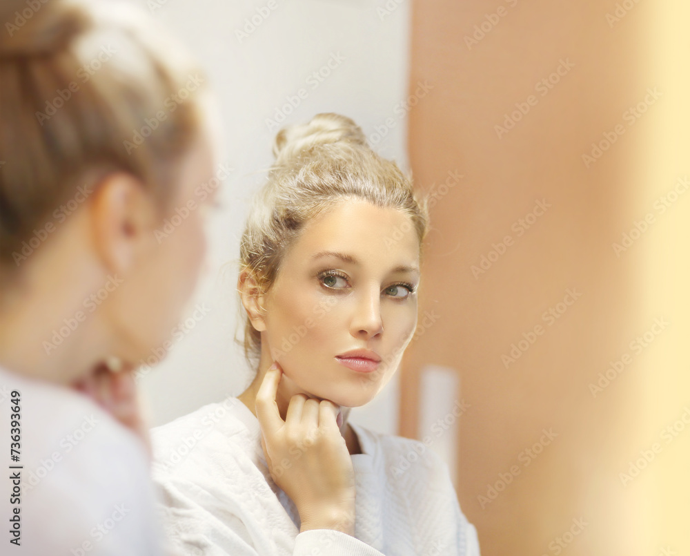 Fototapeta premium woman looking in the mirror in the bathroom and taking care of her skin.