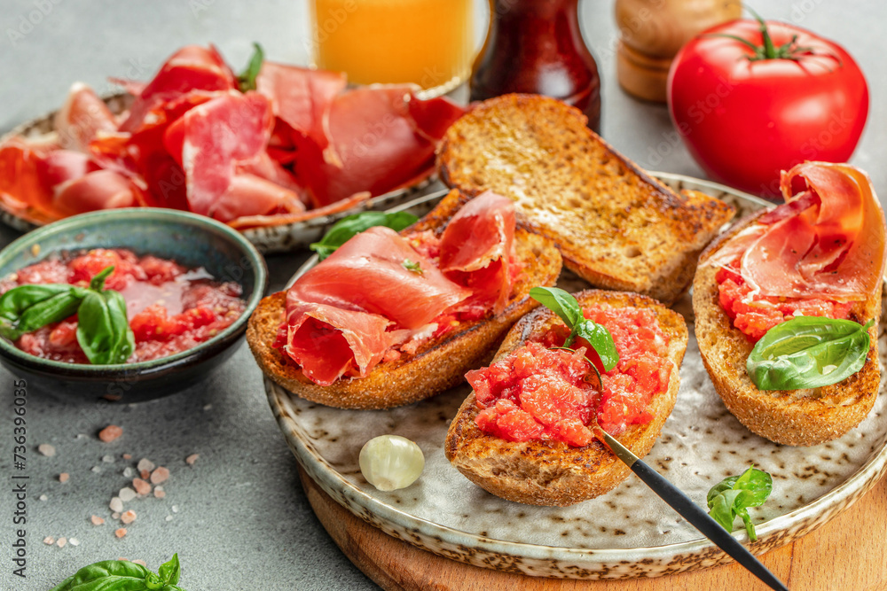 Spanish breakfast. Jamon Iberico ham and tomate bread with coffee and juice on a light background