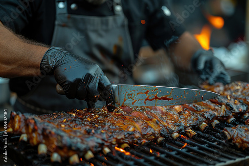 Close-up hand of A chef in black cooking gloves uses a knife to cut smoked pork ribs.