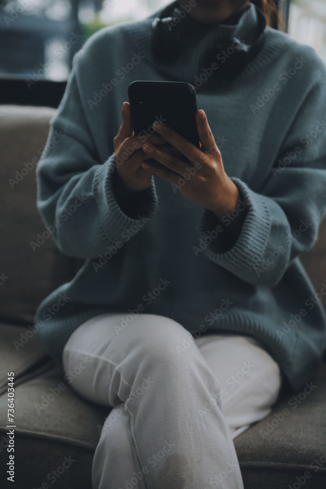 Happy pretty millennial Indian girl relaxing at home, resting in armchair, typing on smartphone, using online app, software, shopping on Internet, making video call. Mobile phone communication Happy pretty millennial Indian girl relaxing at home, resting in armchair, typing on smartphone, using online app, software, shopping on Internet, making video call. Mobile phone communication