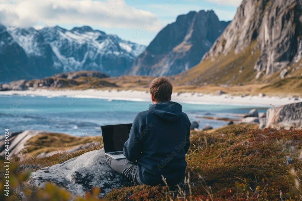 A person sits on a sturdy rock while using their laptop to work, providing a scenic view of the expansive ocean, An IT professional working remotely from a serene location, AI Generated