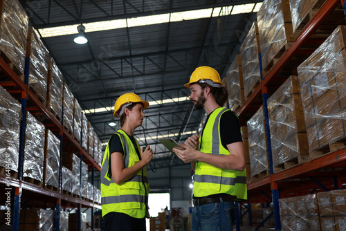 Two distribution warehouse coworkers are walking using a digital tablet to check inventory on a physical count