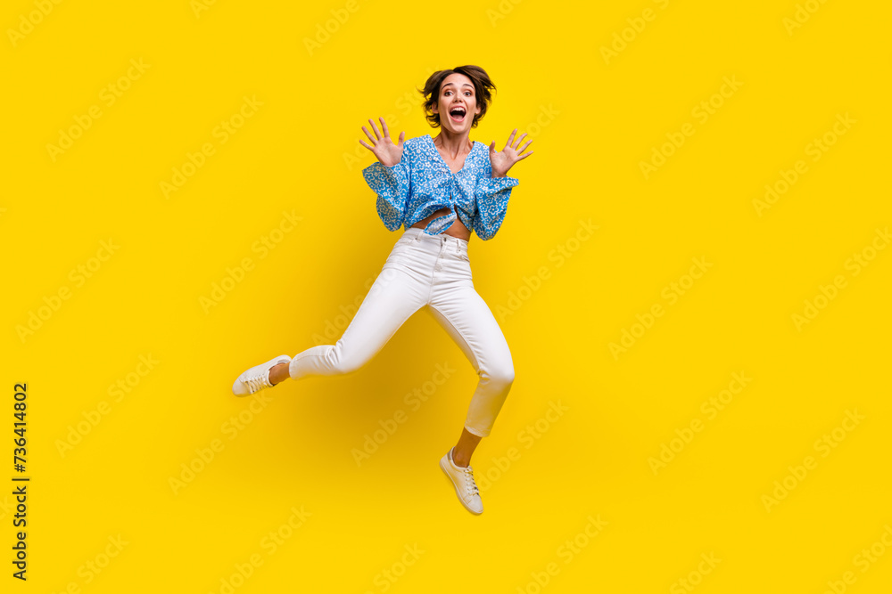 Full size photo of overjoyed ecstatic woman wear print blouse flying show palms astonished staring isolated on yellow color background