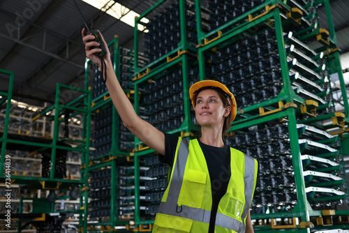 At the raw material storage in the warehouse distribution, there is a portrait of a young woman wearing a green safety reflector vest, who is ready to supply materials to the production line. photo