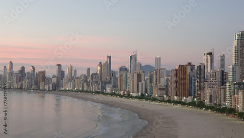 Sunrise on Balneário Camboriú beach, Santa Catarina, Brazil, with buildings in the blurred background.