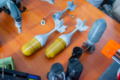 Prototype model of rocket bomb tip printed on 3D printer. Small colored models of tail fins, tail cone printed on 3D printer from molten plastic on table. New modern innovation printing technology