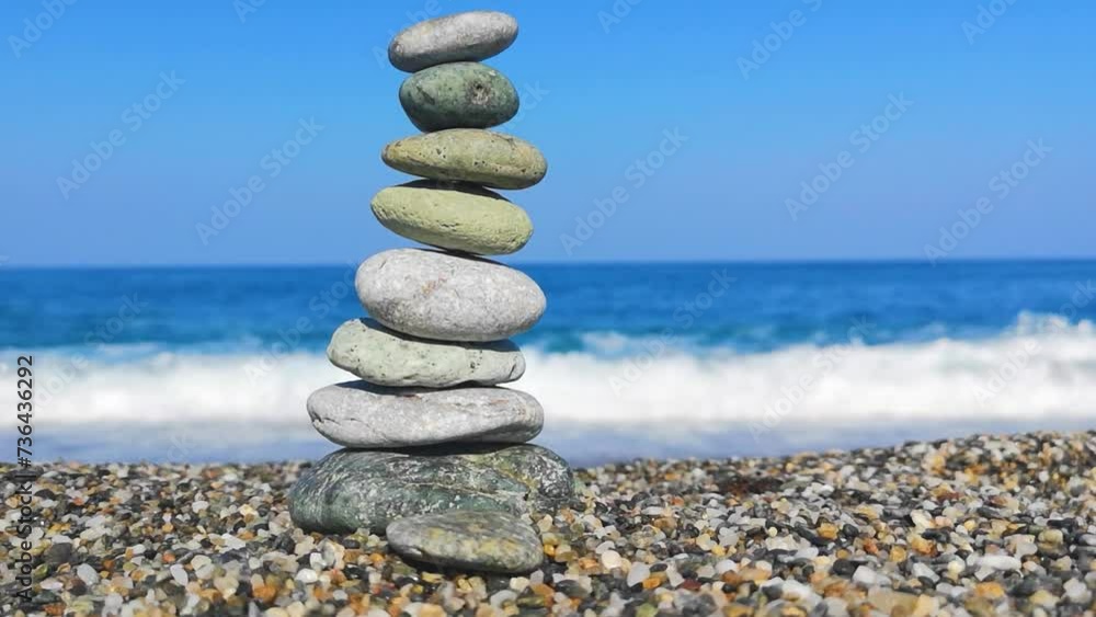 Pyramid of light stones on pebble beach against background sea waves. Ocean shore zen. Concept of calm, yoga, self-improvement, construction, games, travel, tourism Pyramid of light stones on pebble beach against background sea waves. Ocean shore zen. Concept of calm, yoga, self-improvement, construction, games, travel, tourism