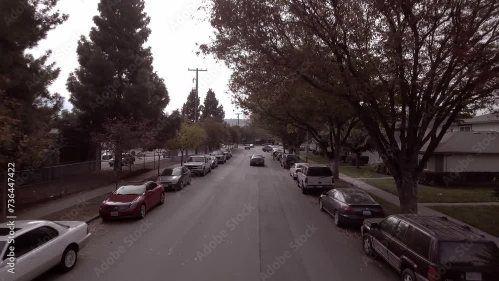 Aerial: Drone Backward Shot Of Cars Parked On Roadside In Residential City Against Clear Sky - San Jose, California