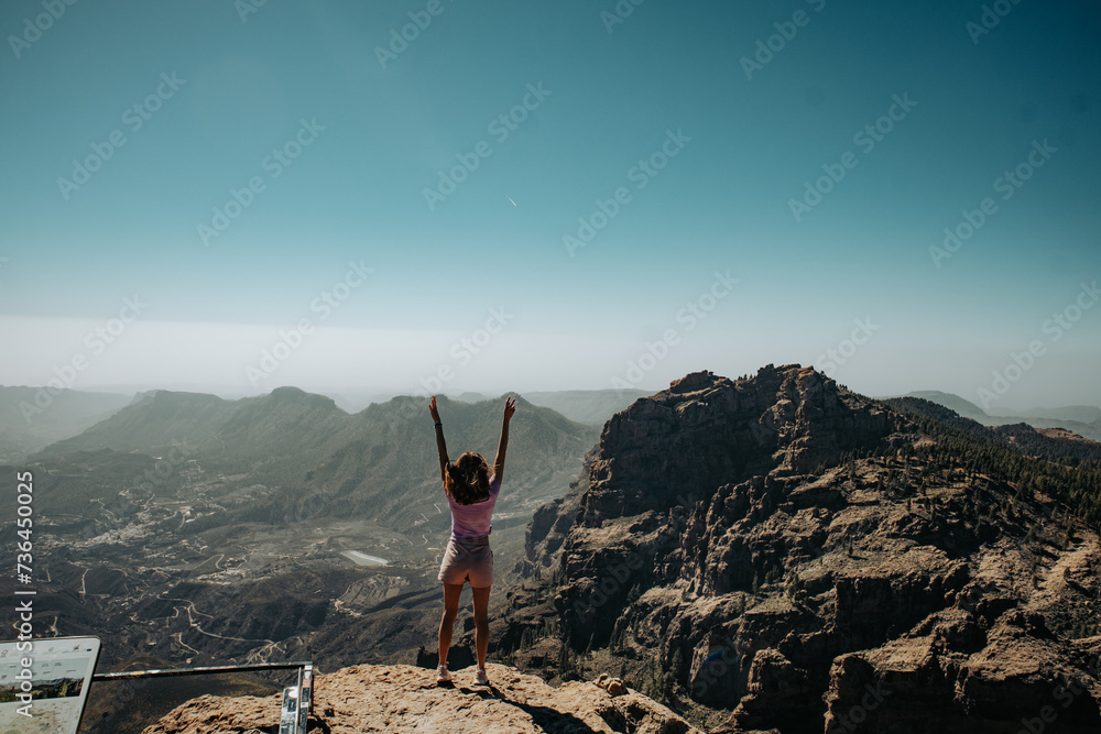 Turystka z podniesionymi rękoma na szczycie góry na wyspie Gran Canaria - obrazy, fototapety, plakaty 