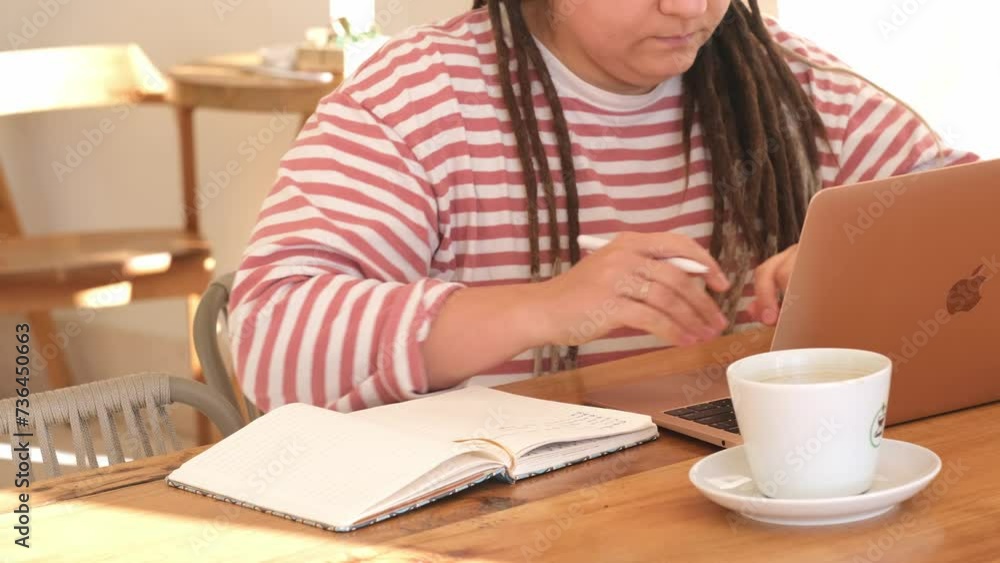 Hipster girl with dreadlocks uses laptop in cafe close up. Female in studying process Hipster girl with dreadlocks uses laptop in cafe close up. Female in studying process