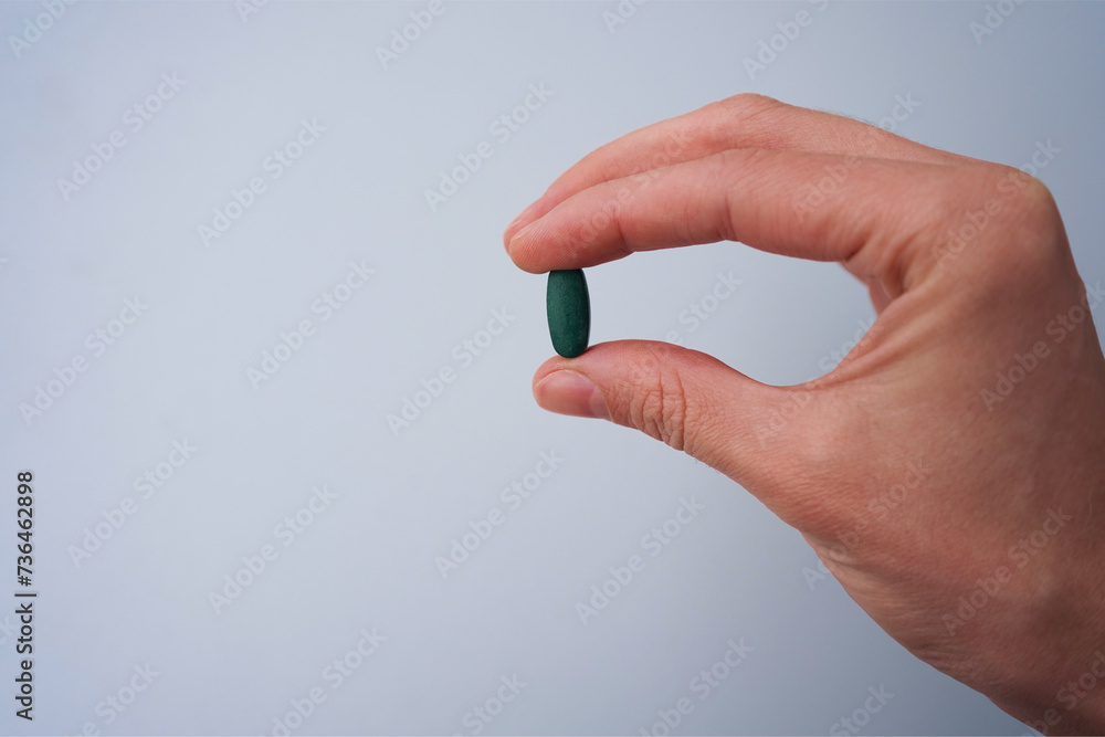 hand with pills green chlorophyll - obrazy, fototapety, plakaty 