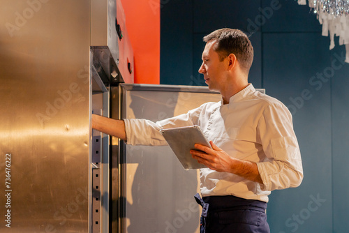 professional kitchen chef looks into the fridge and chooses ingredients for cooking food concept photo