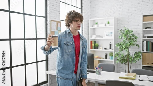 Wallpaper Mural Casual young man with curly hair drinking coffee in a modern office setting, exemplifying a relaxed work environment Torontodigital.ca