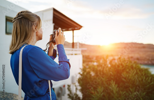 A woman tourist takes pictures of the sunset.