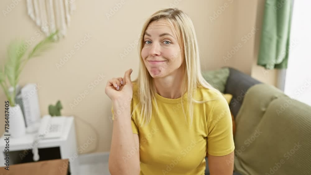 Attractive blonde woman in a t-shirt secretly zipping her lips with her finger, maintaining a silent communication in the comfort of her home. Attractive blonde woman in a t-shirt secretly zipping her lips with her finger, maintaining a silent communication in the comfort of her home.