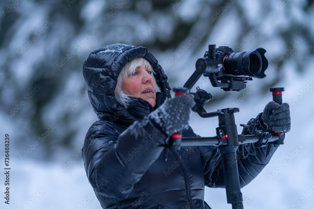 Woman in a down jacket holds a stabilizer with a camera