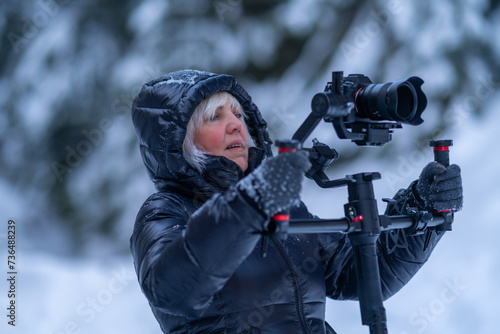 Obraz na płótnie Woman in a down jacket holds a stabilizer with a camera w salonie
