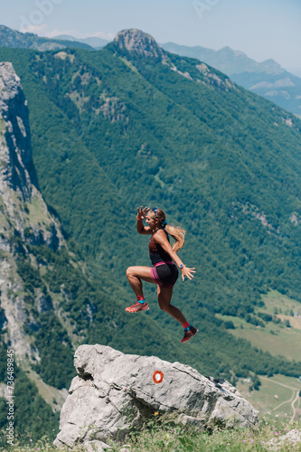 An extreme sportswoman is practicing skyrunning in rocky mountains.