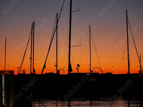 Fototapeta Naklejka Na Ścianę i Meble -  Embankment in the port. Yacht masts and ships sway on waves. Evening. Lantern