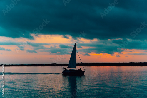 silueta de barco de vela navegando en laguna de bacalar quintana roo mexico al amanecer photo