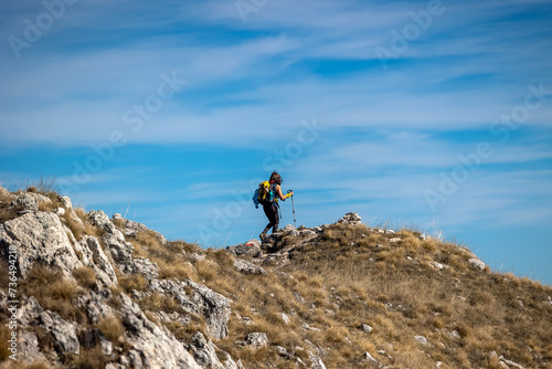 Hiker walk on the mountain path, helping themselves up the climb with trekking poles.