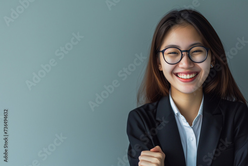 Copy space of a young entrepreneurial businesswoman, on a blue and gray background, cheerful Asian worker with glasses and suit, successful and satisfied in her profession