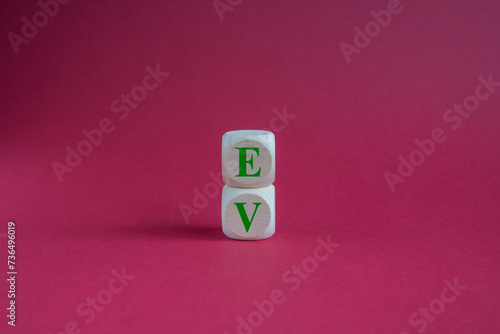 Wooden cubes with green word EV, on red background means electric car for campaign of save world, alternative, modern lifestyle concept. Copy space