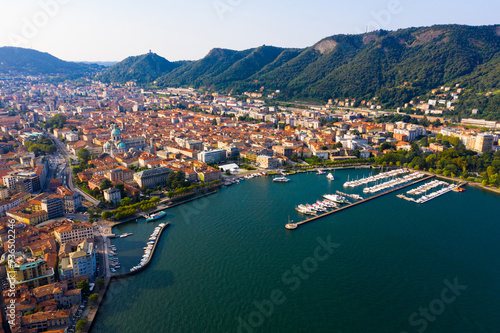 Picturesque view of city of Como on shore of Lake Como on background of mountain at sunny morning, Italy