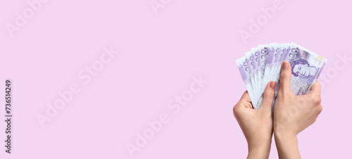 Female hands holding money on lilac background with space for text photo