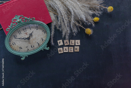 Daylight savings time, Fall Back, flat lay with antique style clock and pampas grass on black background photo