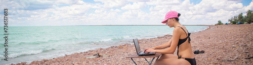 a girl in a sexy swimsuit working at a table on the ocean surf, working remotely from the office,