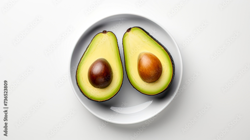Minimalist shot with white plate, avocado halves on clean background.