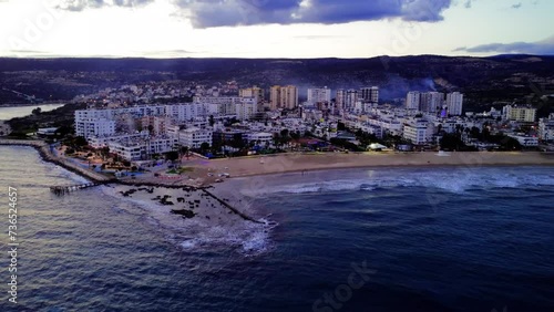 Drone gracefully glides over the sea along the coastal Mediterranean city line at sunset in Turkey. Enjoy the drone view, capturing the mesmerizing twilight scenery photo