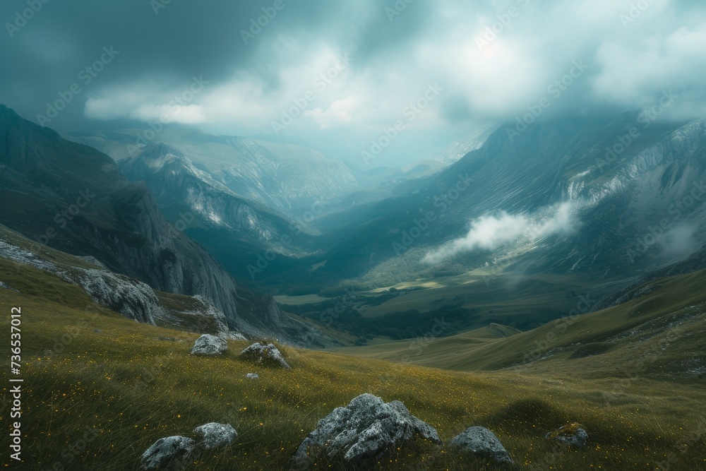 Fototapeta premium Misty mountain landscape with a lush green valley under a cloudy sky.