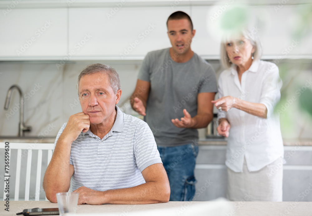 Adult man sits at table and thinks how to resolve conflict with his wife and son