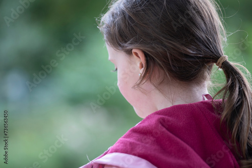 Portrait of a cute little girl with ponytail in the park