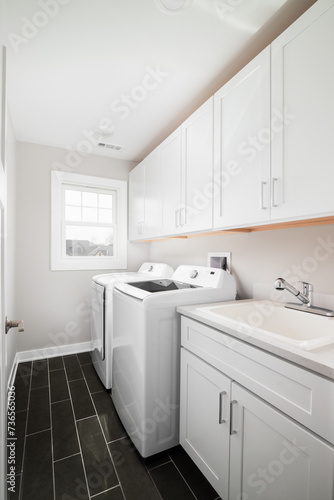 Wallpaper Mural A laundry room with dark grey tiled floor, white cabinets and appliances. No brands or labels. Torontodigital.ca