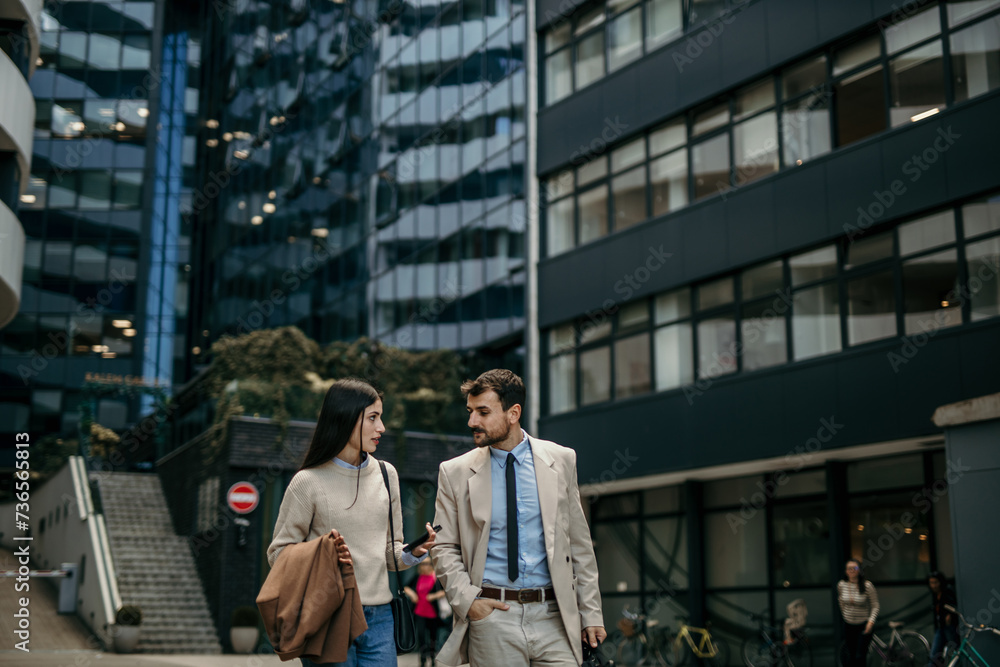 Professional colleagues deep in discussion during their morning commute through the urban business landscape