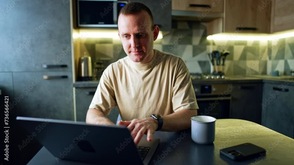 Caucasian male working on laptop in his kitchen. Freelance, remote work from home. Caucasian male working on laptop in his kitchen. Freelance, remote work from home.