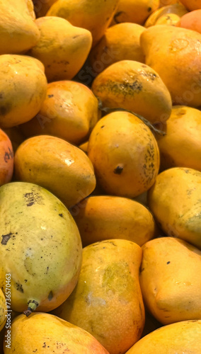 Golden mangoes in tall vertical orientated fruit product display as would be seen in a produce market
