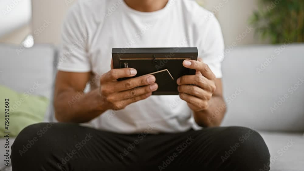 Handsome hispanic man holding a black wallet at home, showing modern interior lifestyle. Handsome hispanic man holding a black wallet at home, showing modern interior lifestyle.