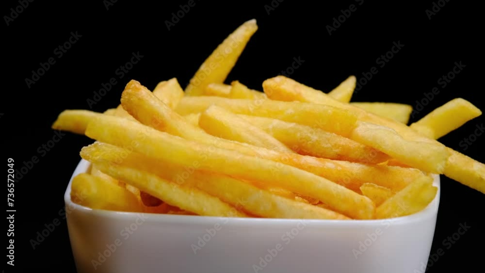 French fries in a white plate on a black background. Fast food. Junk food. French fries in a white plate on a black background. Fast food. Junk food.