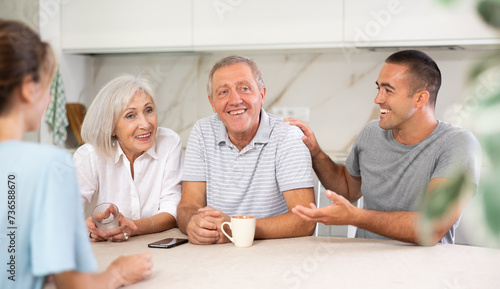 Family (mother, father, son, daughter) having fun talking in kitchen with each other