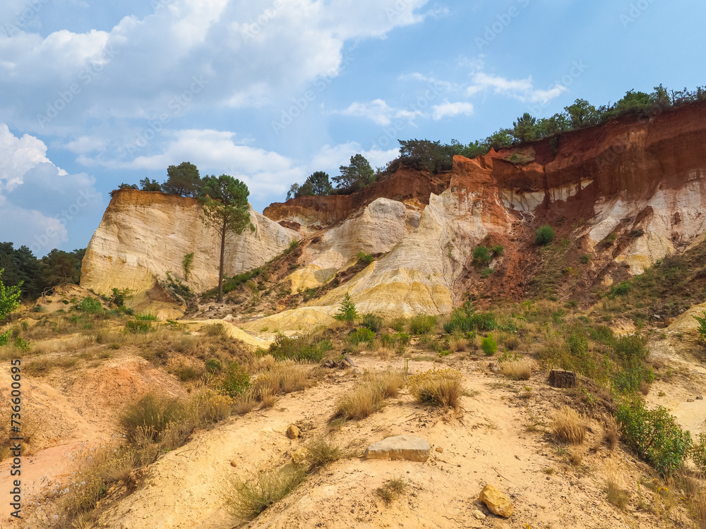 Fototapeta premium The Provence Colorado. Walks in strange desert scenery with yellow red rock formations in former ocher-mining quarries. Rustrel, France. Spectacular colorful valley. Magical view. Beautiful landscape.