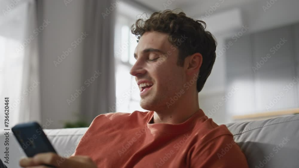 Happy brunette texting cellphone sitting sofa closeup. Joyful man typing sms Happy brunette texting cellphone sitting sofa closeup. Joyful man typing sms