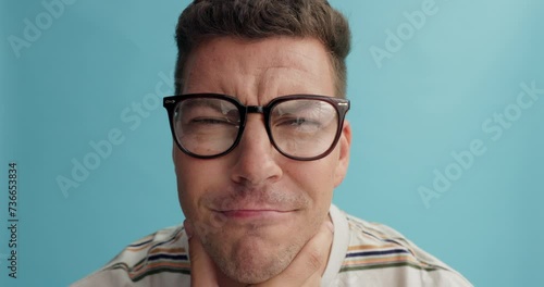 Thinking, face and man with glasses in studio for brainstorming, problem solving or idea on blue background. Why, questions or model portrait with plan emoji for solution, memory or guess expression photo
