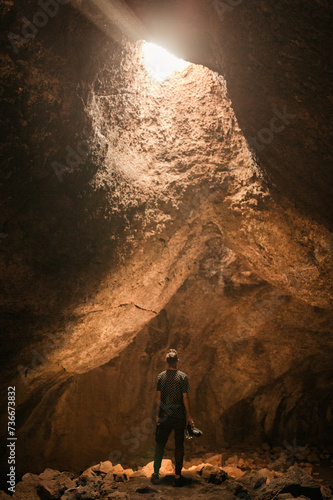 man in a cave looking up at the sun