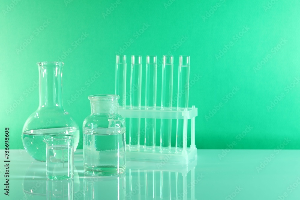 Laboratory analysis. Different glassware on table against green background, space for text Laboratory analysis. Different glassware on table against green background, space for text