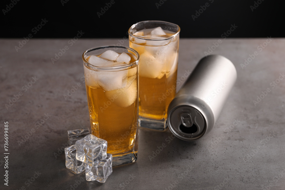 Energy drink in glasses, aluminium can and ice cubes on grey table Energy drink in glasses, aluminium can and ice cubes on grey table